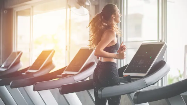 Woman running on a treadmill in a sunny gym